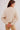 Person wearing a beige textured sweater on a plain background.