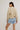 Woman wearing a beige sweater and denim shorts on a plain background.