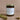 8 ounce Cedar + Oakmoss soy wax candle in an amber glass jar with gold metal lid. Sitting against a soft pink background with oak moss laying to the sides of the candle.