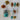 Finial ornaments in chestnut brown, blue and chartreuse with pom poms on a table with books.