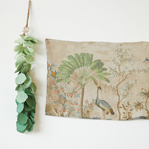 Landscape & Birds Linen Printed Wall Hanging with faux greenery hung next to it. 
