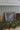 Decorative setup with a framed picture and greenery on a surface against a paneled wall.