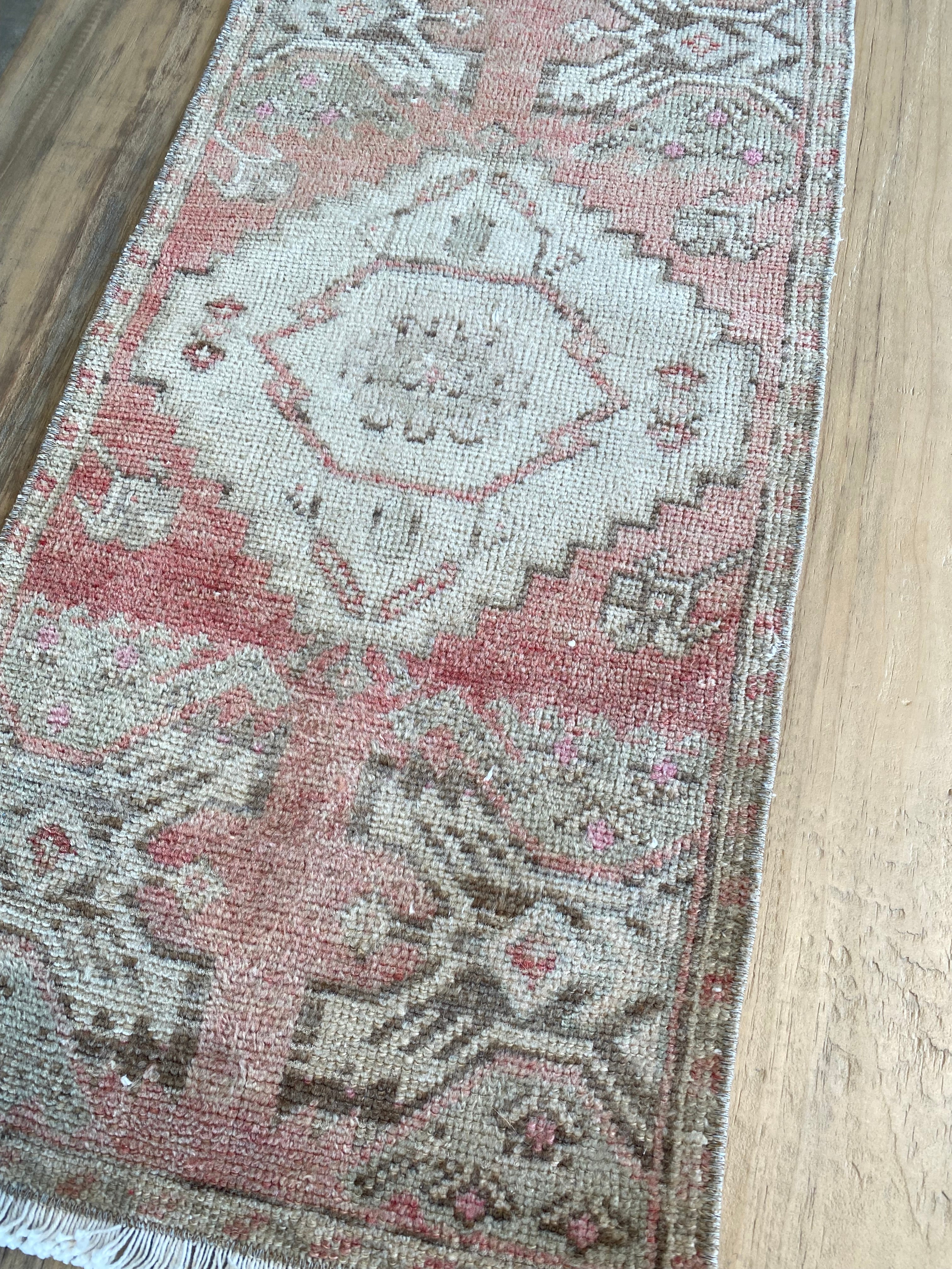 Faded center on a vintage Turkish area rug in pinks and off-whites. 