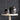 Small and large glazed black vases on top of a white table.