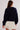 Person wearing a navy sweater and white skirt on a plain background.