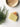 Bar of soap on a white surface with a wooden bowl and greenery.