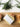 Bar of soap with a white label on a wooden surface, surrounded by greenery.