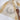 Rabbit Crest Kitchen Towel displayed in a kitchen setting, featuring a natural-colored fabric with mustard-yellow stripes along the edges. The black ink-style illustration of a rabbit framed by a wreath of leaves is visible. A whisk and a wooden spoon rest on the towel, adding a rustic touch.