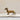 Antique brass dachshund figurine standing on an open book, against a neutral-toned background.