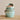 Stacked set of four stoneware measuring cups with an aqua crackle glaze, featuring rustic edges and a speckled finish. The top cup is labeled "1/4 CUP" and filled with small granules, highlighting the functional design. The organic shape and handcrafted appearance add a vintage charm.