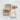 Three soft washcloths in neutral tones—taupe, beige, and off-white—laid on a textured white surface. Each cloth features a subtle grid pattern. Two small, rustic bars of soap rest beside them, adding to the natural, spa-like aesthetic.