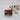 Collection of handcrafted felt mushrooms and berries in various shapes and colors, spilling out of a small cardboard box onto a textured white surface. The whimsical assortment features earthy tones, pops of red and green, and intricate details, evoking a woodland-inspired aesthetic.
