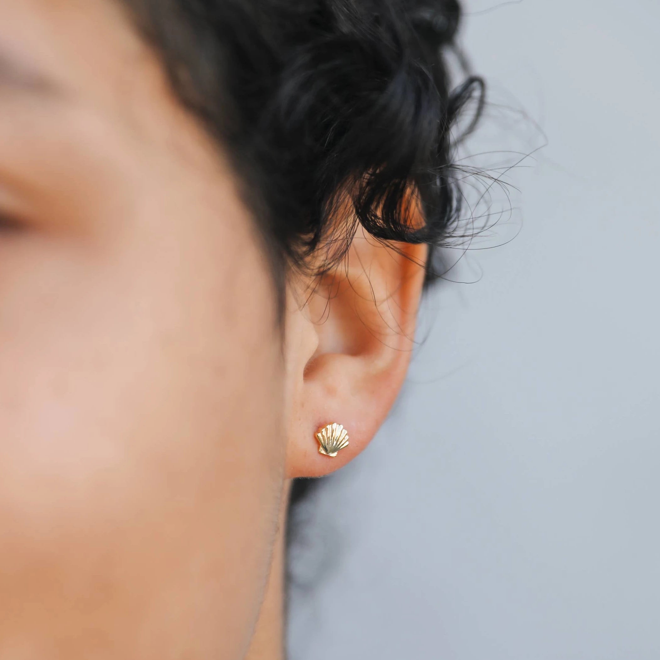 Woman wearing the golden seashell earrings .