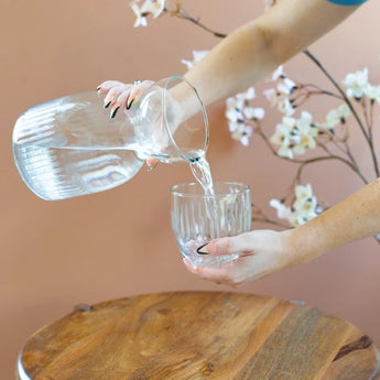 Model pouring water out of the glass carafe with matching glass.