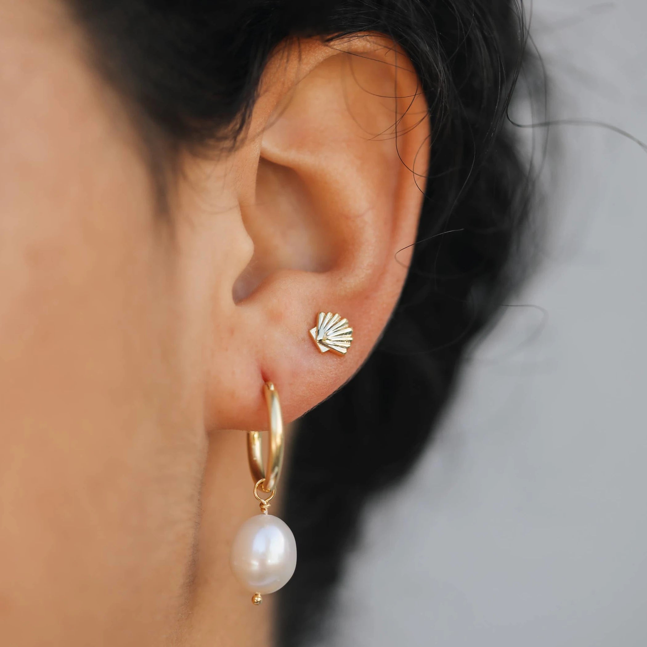 Gold plated seashell earrings styled with an elegant pearl earring. 