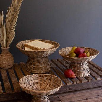 Three sizes of wicker compotes styled with books and fruit.