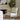 Chair with wooden frame and beige cushion in a room with a fireplace and plant.