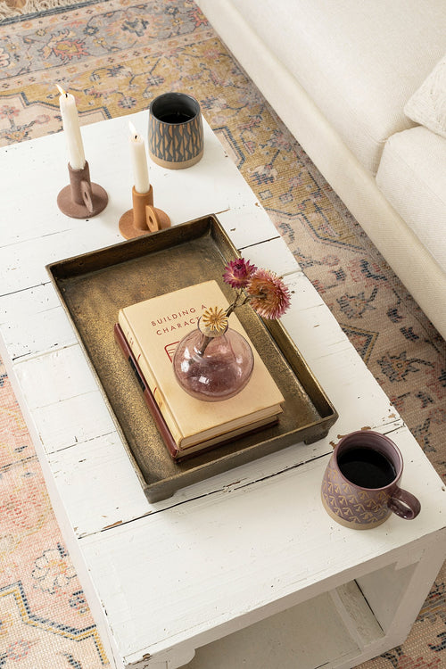Coffee table metal tray styled on top of a wooden table with flowers, candles and coffee. 