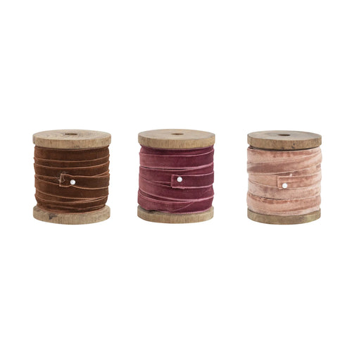 Brown, burgandy and pink velvet ribbons on wooden spools. 