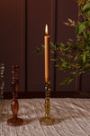 A single caramel coloured taper candle burning in the amber glass Raywood budvase. 