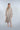 Woman wearing a beige robe that's open on a plain background
