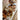 A gold measuring spoon laying on a counter next to stoneware vessels filled with seeds, nuts and freshly baked bread. 