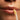 Close-up of a person applying lip serum with a brush to their lips.
