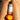 Body serum bottle labeled 'Beauty from Bees' on a person's skin with an apricot fruit.