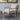 Chair with wooden frame and light gray cushion in a room with a window and concrete floor.