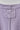 Close-up of a light purple ribbed knit garment showing the inner neck label patch and center seam.