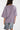 Person wearing a purple oversized t-shirt and denim shorts on a white background