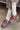 Brown shoes with red laces worn with white socks on a concrete floor.