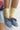 Person wearing yellow socks and blue loafers with a neutral background