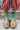 Person wearing green socks with white stripes and brown shoes on a natural background