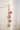 Rustic String of Brass Finish Bells on a jute rope hanging from an antique door painted off white. 