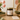 Candle labeled 'Mom' on a table with flowers and books in the background