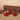 Three red cardinal bird figurines with black feather details are arranged on a beige surface in front of a brown log prop, with small red berries on the left.