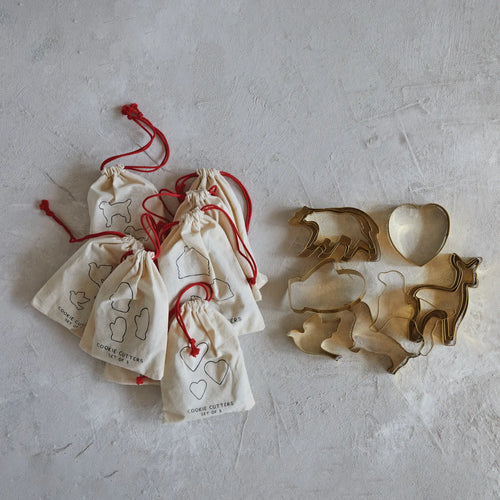 Gold Christmas cookie cutters in a drawstring bag with red tie. 