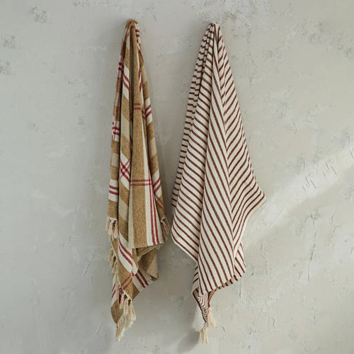 Cotton throws hanging against a textured wall. 