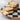 Piled sandwiches on a marble and black checkered board with a jar of creamy horseradish. 