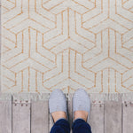 Geometric design in mustard colour on a cream tufted cotton rug. 