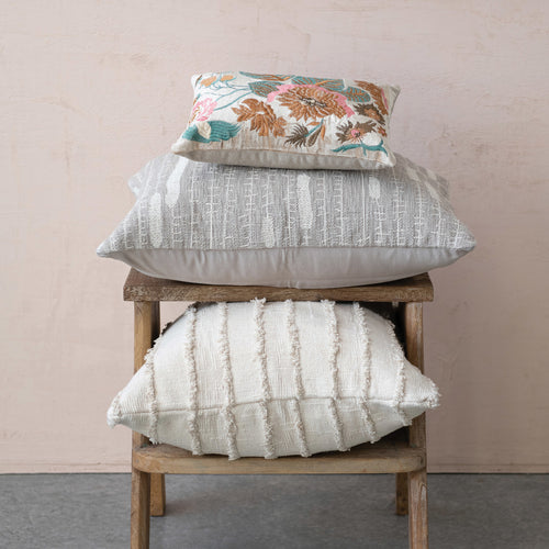 Cotton and Velvet Lumbar Pillow with Floral Embroidery in vibrant colours, stacked on top of larger neutral pillows..