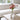 Clear vase with pink flowers on a wooden coffee table in a living room.