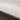 Close-up of a textured white sofa corner with a wooden border.