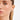 Close-up of a woman wearing silver hoop earrings on a neutral background