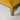 Close-up of a yellow upholstered chair with wooden legs on a light gray background