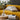 Yellow sofa with striped cushions, a wooden side table, and decorative items in a living room setting.