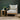 Wooden armchair with a gray cushion next to a small wooden side table with a plant against a dark green wall.