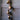 A cluster of four rustic iron bells on a jute rope hanging from a dark blue antique door.