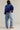 Person wearing a blue denim jacket and light blue jeans on a plain background
